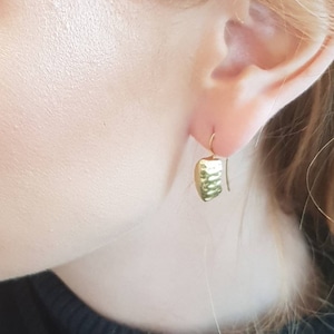 May include: Gold hammered square earrings with a simple hook closure.