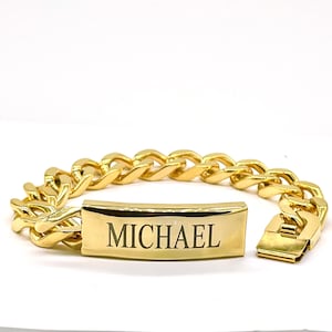 May include: A gold chain bracelet with a rectangular nameplate engraved with the name "MICHAEL".