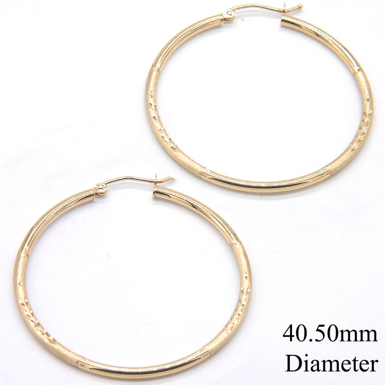 May include: A pair of gold hoop earrings with a textured surface. The earrings are 40.50mm in diameter.