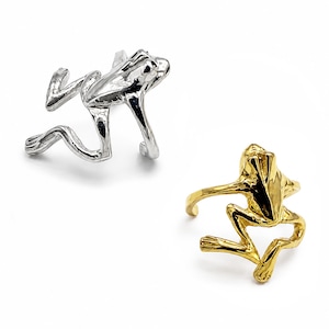 May include: Two rings shaped like frogs, one in a polished silver-tone finish and the other in a polished gold-tone finish. Each ring features a detailed frog figure with extended legs that form the band, showcasing a smooth, reflective surface.