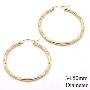 May include: A pair of gold hoop earrings with a textured design. The earrings are 34.50mm in diameter.