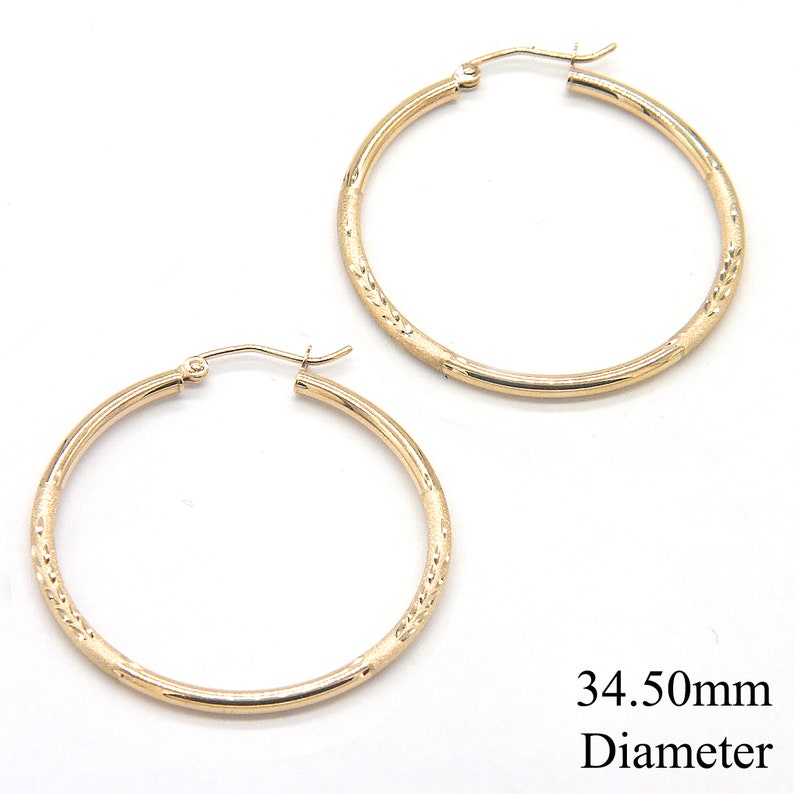 May include: A pair of gold hoop earrings with a textured design. The earrings are 34.50mm in diameter.