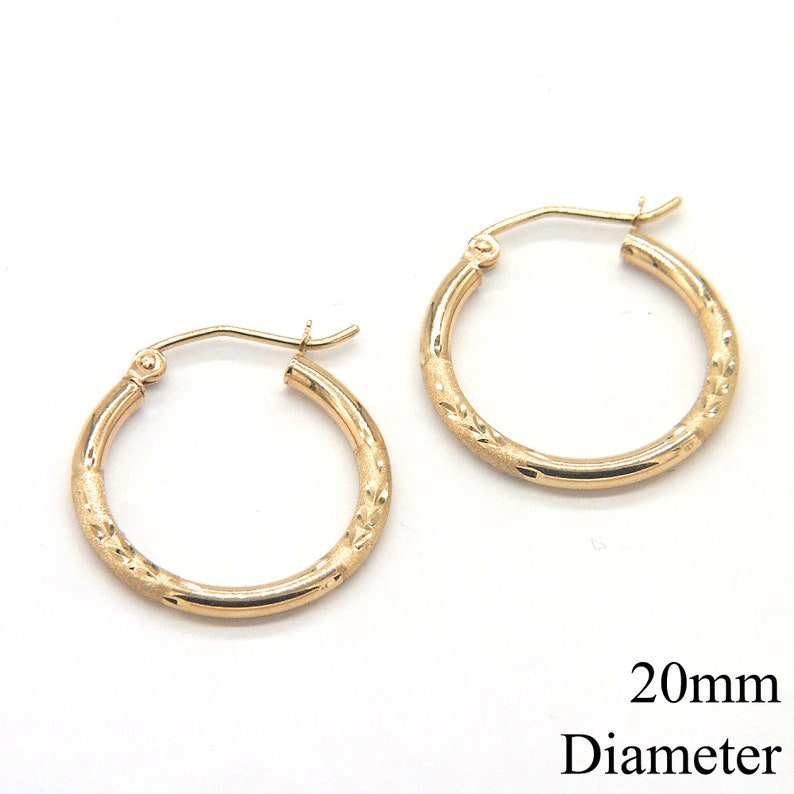 May include: A pair of gold hoop earrings with a textured design. The earrings are 20mm in diameter.