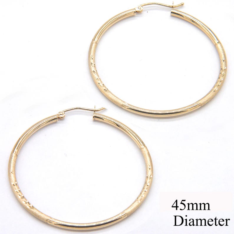May include: A pair of gold hoop earrings with a textured surface. The earrings are 45mm in diameter.