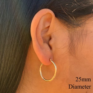 May include: Gold hoop earrings with a textured finish. The earrings are 25mm in diameter.