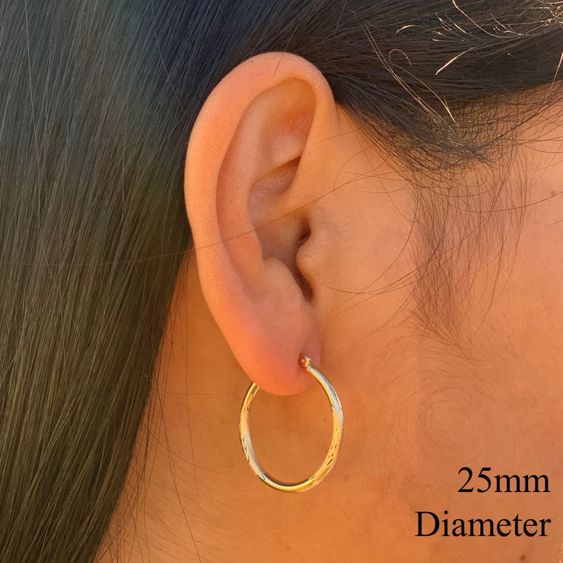 May include: Gold hoop earrings with a textured finish. The earrings are 25mm in diameter.