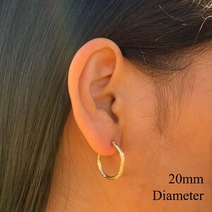 May include: Gold hoop earrings with a textured design. The earrings are 20mm in diameter.