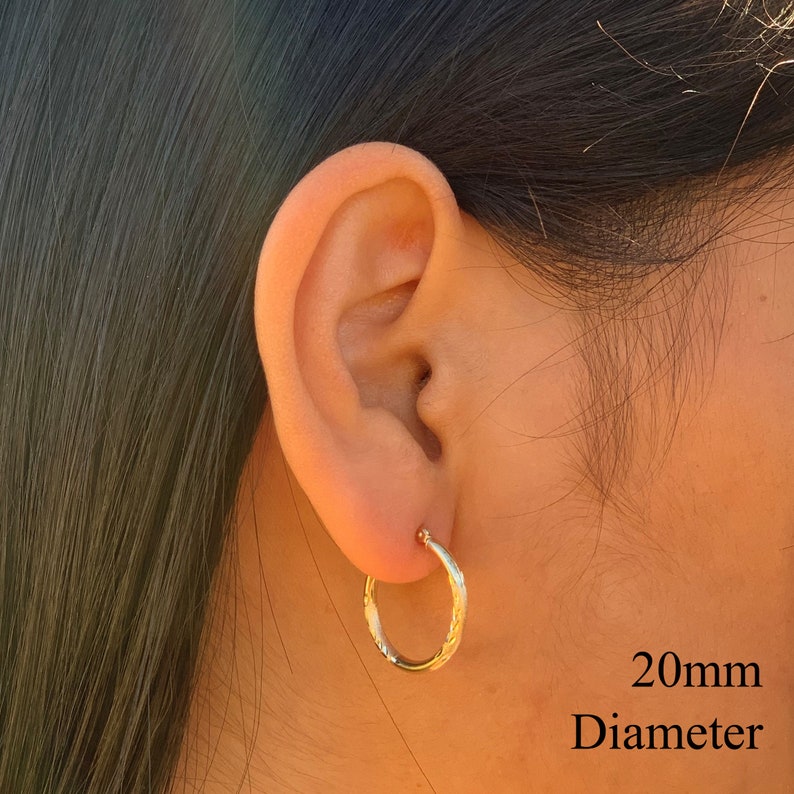 May include: Gold hoop earrings with a textured design. The earrings are 20mm in diameter.