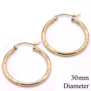 May include: A pair of gold hoop earrings with a textured design. The earrings are 30mm in diameter.