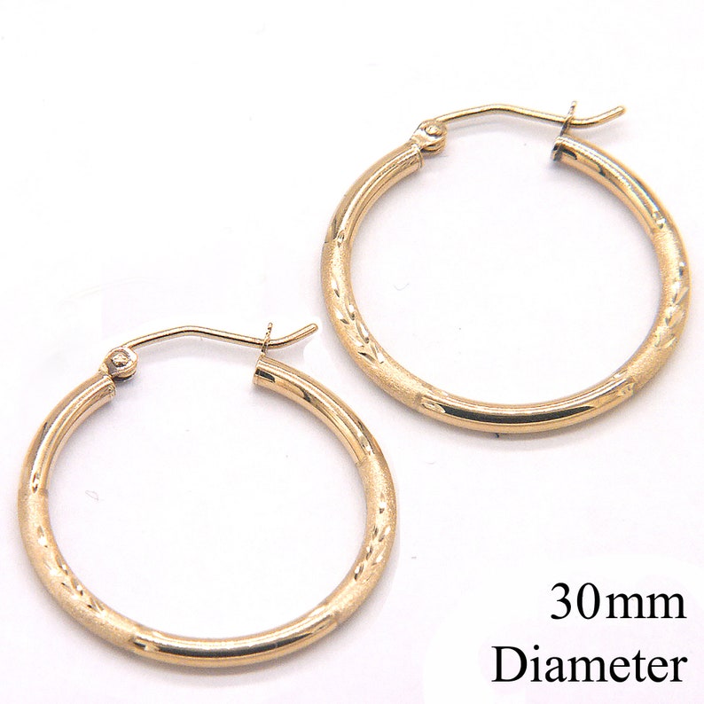 May include: A pair of gold hoop earrings with a textured design. The earrings are 30mm in diameter.