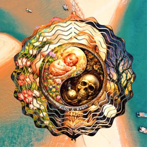 May include: A circular metal wind spinner featuring a yin-yang design. One side depicts a sleeping infant surrounded by colorful flowers, while the other side shows a human skull. The text "Birth & Death" is printed at the bottom center.