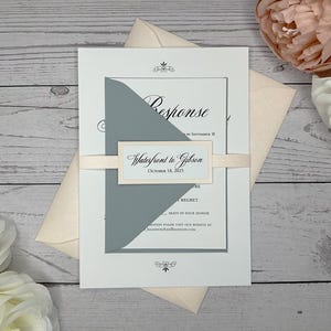 May include: A white wedding invitation with a gray inner envelope. The invitation features the text "Response" and "Waterfront to Gibson" with the date "October 18, 2023".