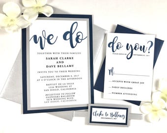 May include: Wedding invitation with navy blue and silver accents. The invitation reads "we do" and includes the names Sarah Clarke and Dave Bellamy, the wedding date, and the location. The RSVP card reads "do you?" and includes a space for the guest to indicate their attendance.