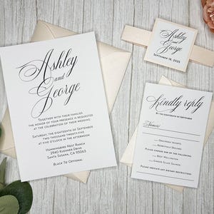 May include: Wedding invitation suite with white cardstock and black calligraphy. The invitation features the names "Ashley and George" and the wedding date "September 18, 2025". The RSVP card includes the text "Kindly reply by the eighteenth of September".