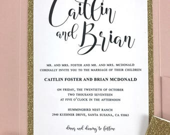 May include: A pink and gold wedding invitation with the text "Caitlin and Brian" in cursive script. The invitation details the wedding date, time, and location: Friday, October 20th, 2017 at 5:00 PM at Hummingbird Nest Ranch, 2940 Kuehner Drive, Santa Susana, CA 93063. The invitation also includes the text "dinner and dancing to follow".