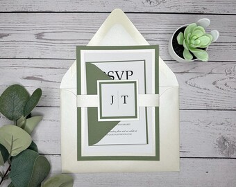 May include: A green and white wedding invitation with a white envelope. The invitation has a green border and a white inner layer with the text "RSVP" and "JT" in black. The envelope is white with a subtle texture.