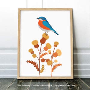 May include: A framed art print featuring a blue and orange bird perched atop stylized brown and yellow thistle flowers. The artwork is set against a white background and framed in a light wood frame. The print has a minimalist, nature-inspired theme.