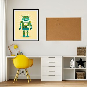 May include: A framed illustration of a green and blue robot with a yellow face and a yellow dial on its chest. The robot is standing on a yellow background with a yellow sunburst behind it.