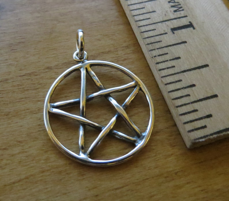 May include: Silver pendant featuring a pentacle, a five-pointed star within a circle. The star is made of thick, twisted wire.