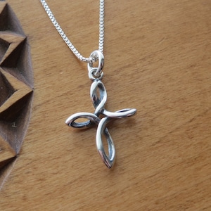 May include: A silver Celtic knot cross pendant necklace. The cross is made of a single piece of twisted wire, creating a delicate and intricate design.