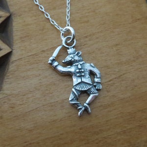 May include: A silver necklace with a charm of a rat dressed as a soldier holding a sword.