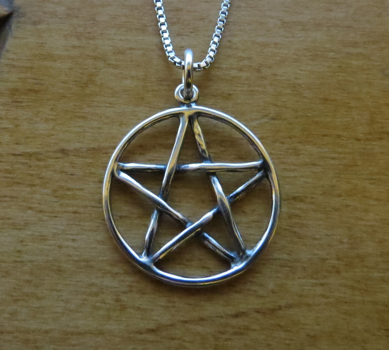 May include: A silver pendant necklace featuring a pentacle, a five-pointed star within a circle, with a detailed, woven design.