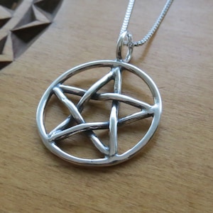 May include: A silver pendant necklace featuring a pentacle, a five-pointed star within a circle, on a silver chain.