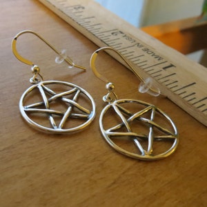 May include: A pair of silver earrings featuring a pentagram design. The earrings are made from sterling silver and have a simple, elegant design.