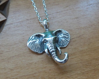 May include: A silver elephant head pendant necklace. The pendant is detailed and realistic, with textured ears and a curled trunk.