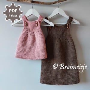 Puede incluir: Dos vestidos de bebé de punto, uno rosa y otro marrón, cuelgan de perchas blancas. Los vestidos tienen detalles de botones en las correas. La imagen incluye el texto "PDF 4 sizes" y el copyright "© Breimeisje".