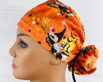 May include: Orange and black scrub hat with a Halloween theme featuring witches and bats. The hat has a black tie and a star pattern.