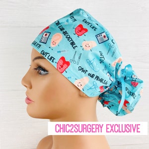 May include: A light blue surgical scrub hat with a fun print featuring cartoon ears, hearts, and the text "ENT Life", "Ear-Resistible", and "Snot Our Problem".
