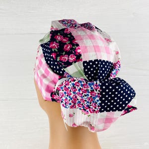 May include: A patchwork scrub cap featuring a variety of fabric patterns. The cap includes pink gingham, navy blue polka dots, floral prints, and a navy blue floral pattern. The cap is designed to be worn during medical procedures.