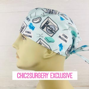 May include: A light blue surgical scrub hat with a pattern of medical equipment, including a washing machine, surgical gloves, and scissors. The hat has a tie at the back. The text "Sterile Processing" is printed on the hat.