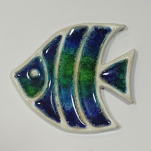 May include: A ceramic fish-shaped decorative item with a white border. The fish features blue and green sections, with a glossy finish. The design includes a circular eye and a triangular fin. The item is suitable for home decor.