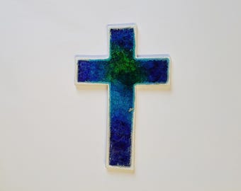 Könnte beinhalten: Ein blaues und grünes Buntglaskreuz mit weißem Rand.