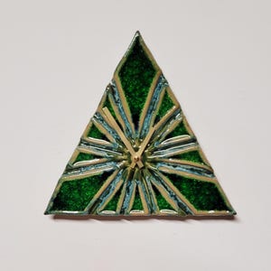 May include: A green and blue triangular clock with gold hands. The clock face has a geometric design.