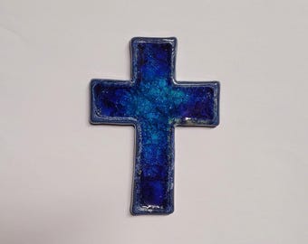 Könnte beinhalten: Ein blaues Glaskreuz mit einer strukturierten Oberfläche. Das Kreuz besteht aus kleinen Glassplittern, die miteinander verschmolzen wurden.