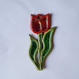 Può includere: Un fiore di tulipano in ceramica rosso e verde con una superficie testurizzata.
