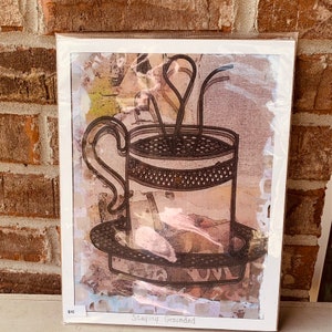 May include: A brown and white art print with a black and white illustration of a coffee cup with steam rising from it. The text "Staying Grounded" is at the bottom of the print.