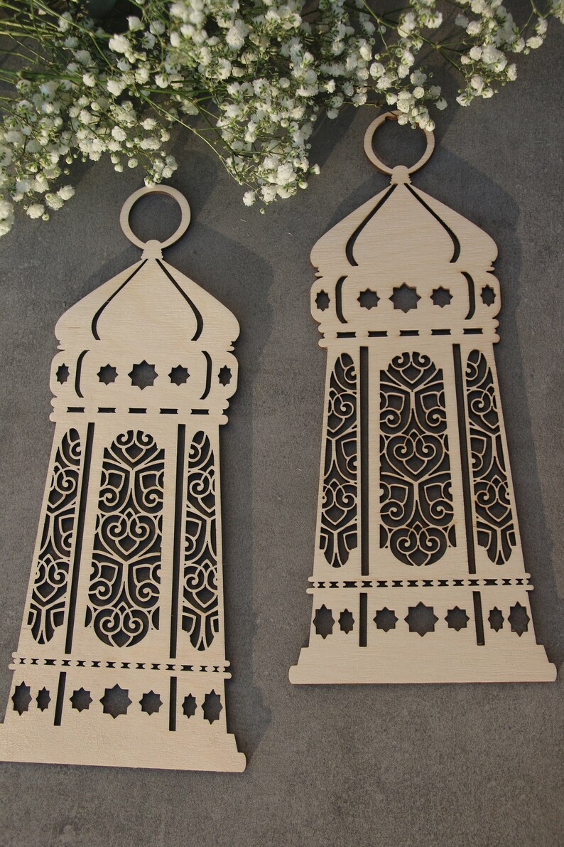 May include: Two wooden decorative lanterns with intricate cut-out designs. The lanterns are light brown and have a traditional Moroccan style.