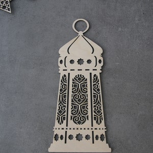 May include: A wooden cutout of a decorative lantern with intricate designs. The lantern is light brown and has a traditional Islamic style.