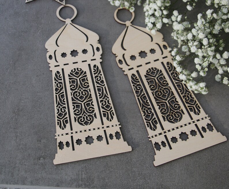 May include: Two wooden cutout lanterns with intricate designs. The lanterns are light brown and have a traditional Moroccan style.