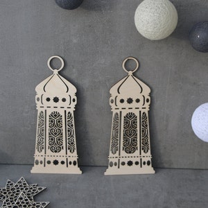 May include: Two wooden laser cut lanterns with intricate designs. The lanterns are light brown and have a white background. The lanterns are hanging from a string of lights.