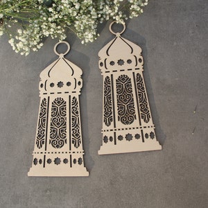 May include: Two wooden decorative lanterns with intricate cut-out designs. The lanterns are beige and have a traditional Islamic style.