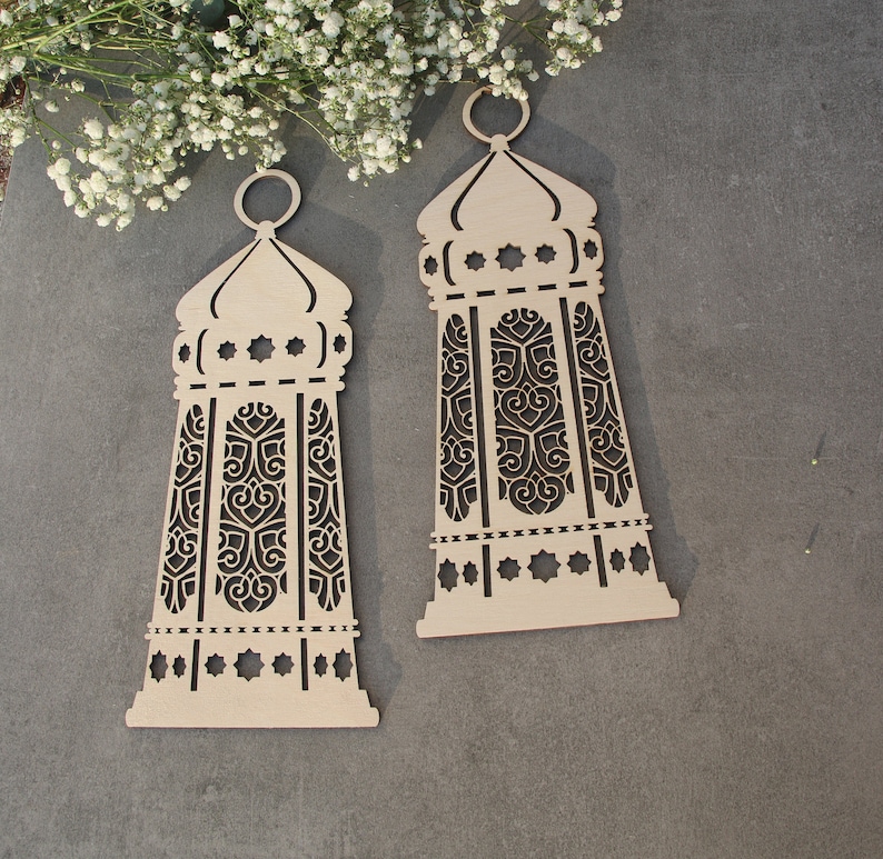 May include: Two wooden decorative lanterns with intricate cut-out designs. The lanterns are beige and have a traditional Islamic style.
