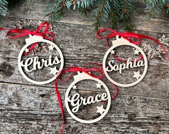 May include: Three wooden Christmas ornaments with red ribbon and the names Chris, Sophia, and Grace.
