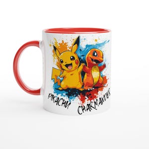 May include: A white ceramic mug with a red rim features a colorful illustration of Pikachu and Charmander from the Pokemon franchise. The background is a splatter of blue, red, and yellow paint. The text "Pikachu" and "Charmander" are written below the characters.