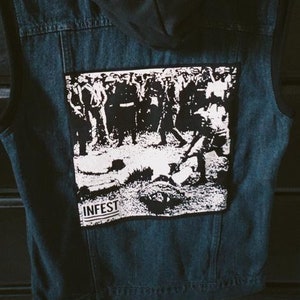 May include: A blue denim vest with a black hooded liner and a black and white patch on the back that says "INFEST".
