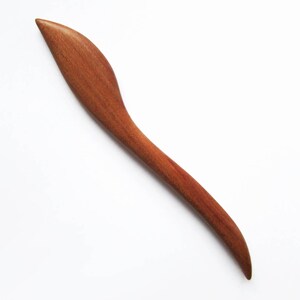 May include: A long, thin, wooden hair stick with a curved, leaf-shaped end. The stick is a reddish-brown color.